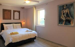 Gites-Terroirs-Occitanie في Felluns: غرفة نوم بسرير مع لوحة على الحائط