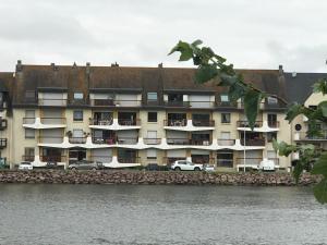 a large building with cars parked in front of the water at Appart 24 avec vue Port in Ouistreham