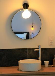 bagno con lavandino rotondo e specchio di Gites-Terroirs-Occitanie a Felluns