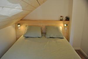 łóżko z 2 poduszkami w małym pokoju w obiekcie Gîte du Fourpéret-Parc Naturel du Haut-Jura w mieście Longevilles-Mont-dʼOr
