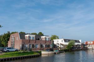 une maison sur l'eau à côté d'une rivière dans l'établissement De Watersport Heeg, à Heeg