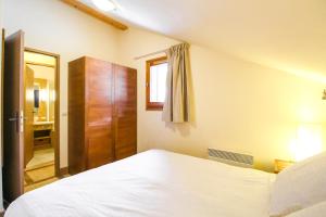 a bedroom with a white bed and a wooden cabinet at Les Terrasses d'Eos, 1-bed apartment with fireplace, Ski in, Ski out in Flaine +45 photos