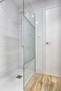 y baño con ducha de cristal y azulejos blancos. en EL Mojon Beach Apartment, en El Mojón