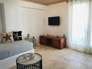 sala de estar con cama, mesa y TV en Klaras House, en Platis Gialos