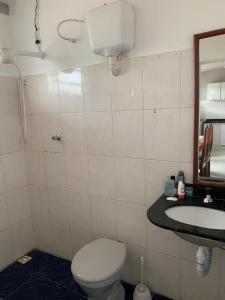 een badkamer met een toilet, een wastafel en een spiegel bij Baixo Guandu, casa independente no Centro. in Baixo Guandu