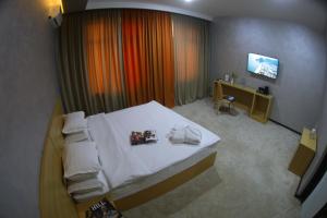a bedroom with a white bed and a television at City INN Hotel in Tashkent