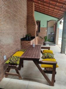 a wooden picnic table with cushions on a patio at Casa a 3 minutos da praia in Saquarema