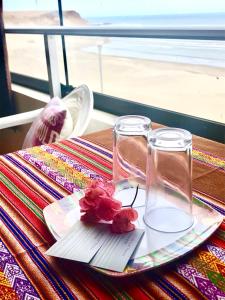 a table with two glasses and a plate with flowers at Surf House Chicama in Puerto Chicama
