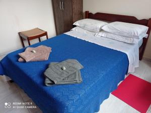 een blauw bed met twee handdoeken erop bij Cunha centro - quarto cama de casal in Cunha