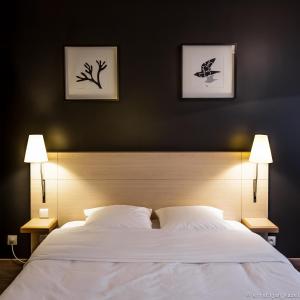 a bedroom with a large white bed with two lamps at Hotel Aviation in Brussels