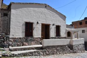 a white building with a door and some stairs at El Caucillar in Iruya