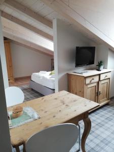 Habitación con mesa, TV y cama. en Casa Lassù., en Carano