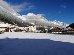a snow covered town with a church and a mountain at Apartments Rainer in Anterselva di Mezzo
