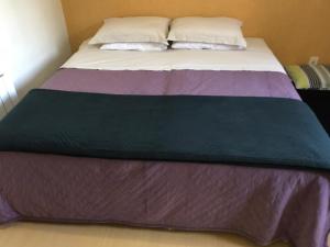 Una cama con una manta morada encima. en Duplex Borges De Medeiros, en Gramado