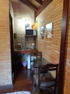 une salle à manger avec une table et un four micro-ondes dans l'établissement Villa Valentina chalés com lareira e churrasqueira, à Campos do Jordão