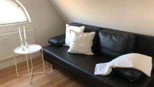 a black leather couch with white pillows and a table at City Apartment in Lörrach