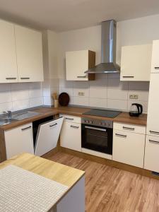 een keuken met witte kasten en een fornuis met oven bij familienfreundliche Ferienwohnung Anna in Rollshausen