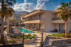 a resort with a swimming pool and palm trees at Riviera Boutique Hotel in Stalida