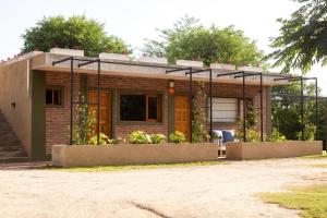 una pequeña casa de ladrillo con un jardín delante de ella en Cabañas de la "USINA" en Cosquín