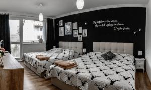 a bedroom with two beds and a black wall at Style Apartment Telgart in Telgárt