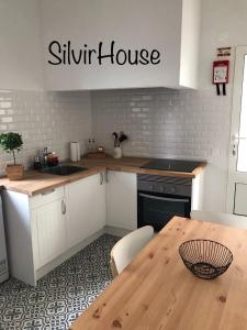 eine Küche mit einem Holztisch und einem silbernen Haus-Schild in der Unterkunft Silvirhouse in Peniche