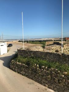 eine Steinmauer neben einer Straße am Meer in der Unterkunft Silvirhouse in Peniche