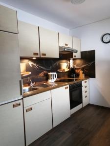 a kitchen with white cabinets and a sink at Ferienwohnungen Panoramablick in Sankt Ulrich am Pillersee