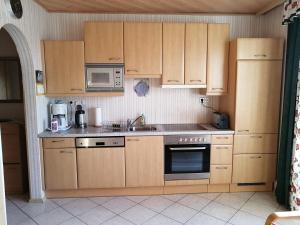eine Küche mit Holzschränken, einem Herd und einer Mikrowelle in der Unterkunft Gästehaus Tropf in Litschau