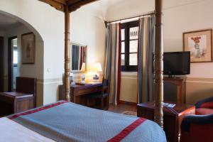 a bedroom with a bed and a desk and a television at Parador de Oropesa in Oropesa
