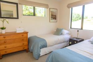 a bedroom with two beds and a dresser and two windows at Arrowtown Country Cottage in Arrowtown