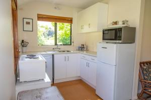 a kitchen with a white refrigerator and a microwave at Arrowtown Country Cottage in Arrowtown