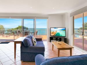 a living room with a couch and a tv and a table at Beachfront Penthouse Cowes in Cowes