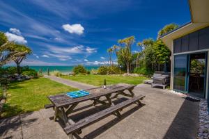 a picnic table on a patio with a view of the ocean at Mohua - Pakawau Holiday Home in Pakawau