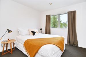 a white bedroom with a large bed and a window at Armagh Apartment 3 - Christchurch Holiday Homes in Christchurch