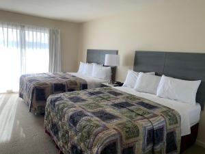a hotel room with two beds and a window at Apple Valley Hotel & Lodge in Apple Valley