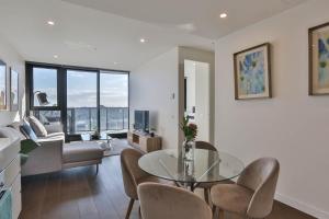uma sala de estar com uma mesa de vidro e cadeiras em Next to 'The Glen Shopping Centre' Apartment em Glen Waverley