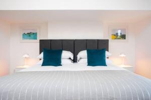 sypialnia z dużym łóżkiem z niebieskimi poduszkami w obiekcie Clifton Jewel - 4 bed townhouse with parking. MyCityHaven w Bristolu