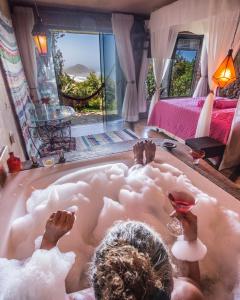 a person laying in a bath tub in a bedroom at Villa Buena Vista in Praia do Rosa