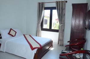 a bedroom with a bed and a window and a chair at DTC Hotel in Da Nang