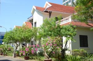 ein weißes Haus mit Bäumen und Blumen davor in der Unterkunft DTC Hotel in Đà Nẵng