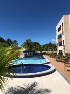 a pool at a resort with tables and chairs at Apartamento em Guarajuba, BAHIA 1 Tudo Novinho e Finamente Decorado in Camacari
