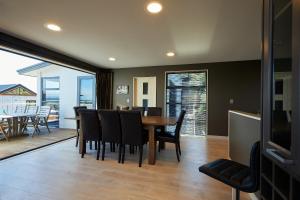 a dining room with a table and chairs and a television at Bliss on the Bay in Kaikoura