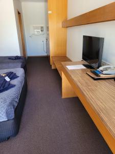 a room with a bed, desk and a laptop at Glynlea Motel in Horsham