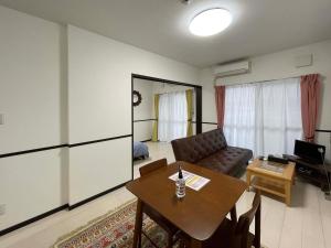 uma sala de estar com uma mesa e um sofá em EX Itoman Apartment 602 em Itoman