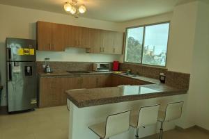 a kitchen with a counter with chairs and a refrigerator at Very comfortable family apartment on Salinas Beach Super fast internet in Salinas