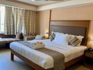 a hotel room with a large bed and a couch at Sai Towers in Puttaparthi