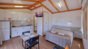 a room with a bed and a table and a kitchen at Cobar Caravan Park in Cobar