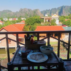 une table avec des assiettes de nourriture sur un balcon dans l'établissement Ninh Binh Greenland Homestay, à Ninh Binh