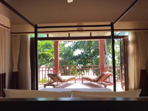 a bedroom with a bed and chairs on a balcony at Amatapura Beachfront Villa 15, SHA Certified in Ao Nam Mao