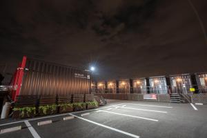 an empty parking lot at night with a building at HOTEL R9 The Yard Isesaki in Isesaki